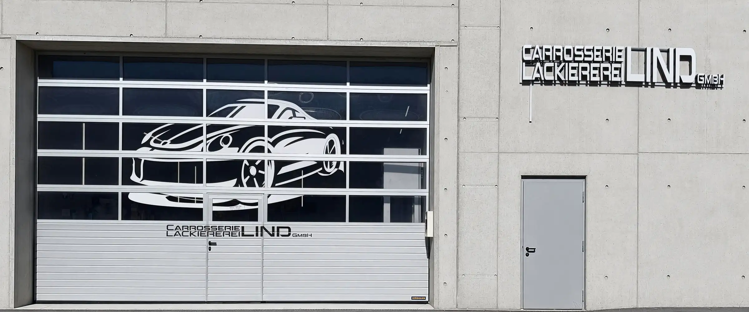 Werkstatthalle mit zwei Fahrzeugen auf Hebebühnen, Tor zum Hof offen
