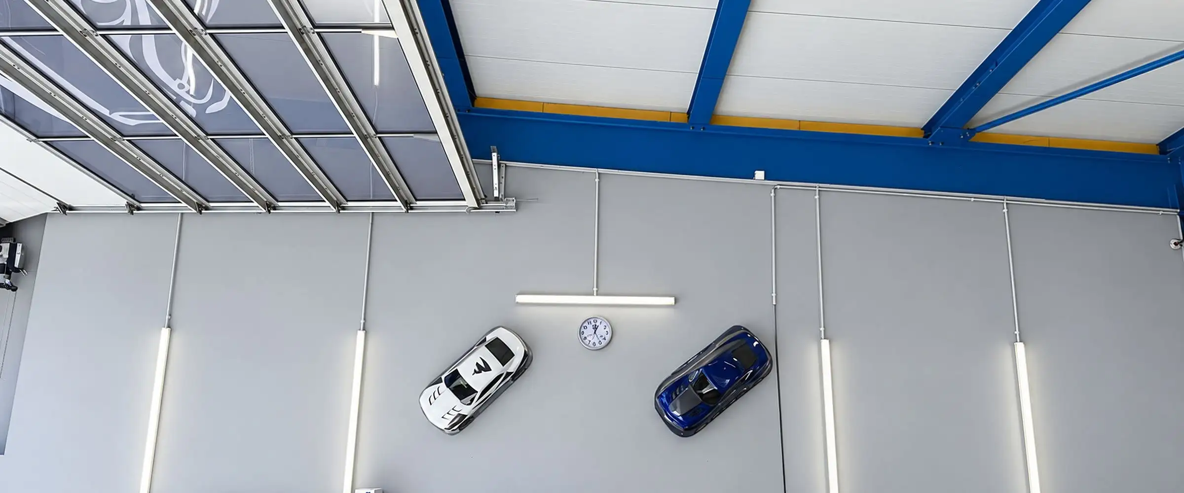 Zwei Modellautos an der hellen Hallenwand über Regalen mit Material