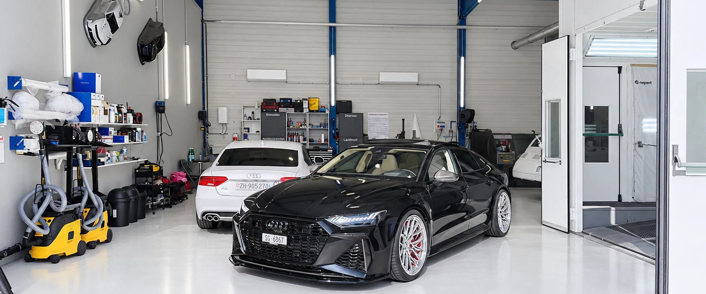 Schwarzer Audi RS7 und weisser Audi A5 in der Werkstatthalle der Carrosserie Lind