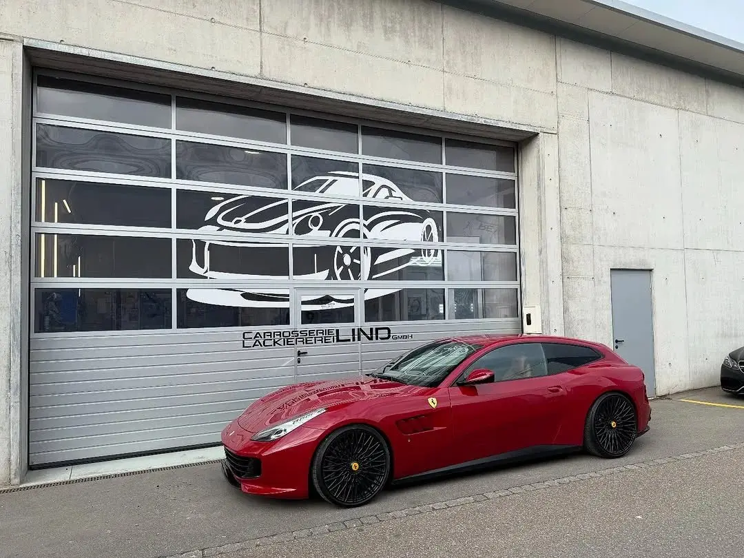 Roter Ferrari GTC4Lusso vor dem Werkstatttor mit dem Lind-Schriftzug
