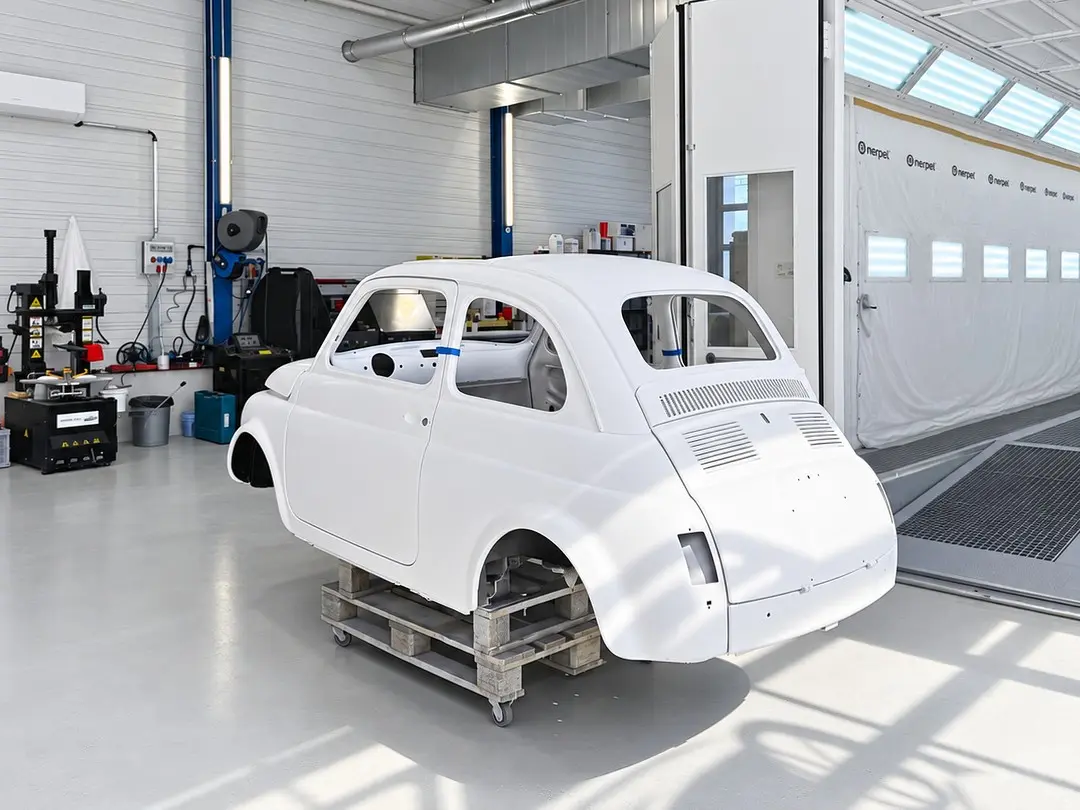 Weisse Karosserie eines Fiat 500 auf einem Rollwagen in der Werkstatt