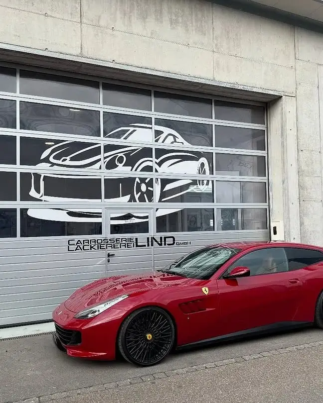 Roter Ferrari GTC4Lusso vor dem Werkstatttor mit dem Lind-Schriftzug