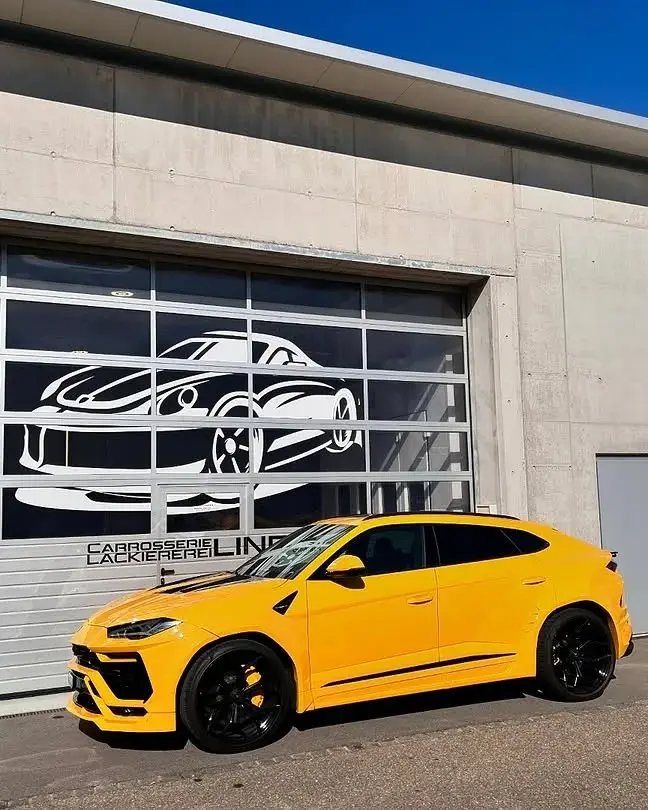 Gelber Lamborghini Urus vor dem Werkstatttor mit dem Lind-Schriftzug